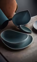 several gray plates are on the table near a brown vase