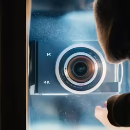 a man is holding a camera to the window