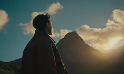 a man is silhouetted by the clouds and mountain peaks