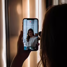 a girl holding up her phone with the camera showing the picture