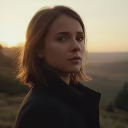 a woman stares off in the distance near mountains