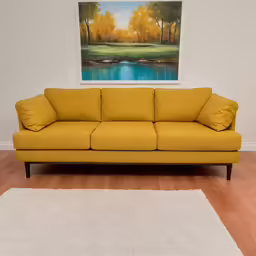 a yellow couch sitting in front of a painting on a wall
