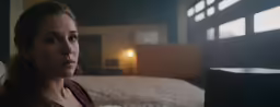 a woman in a dark room near the bed