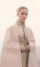 the woman is standing with a cloak on her