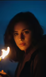a woman holding a lit candle in her hand