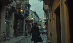 woman with black coat walking on sidewalk in city