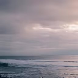 a surfer on the ocean carrying his board under his arm