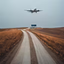 a plane that is flying over a dirt road