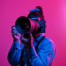 man with a camera taking pictures with pink lighting