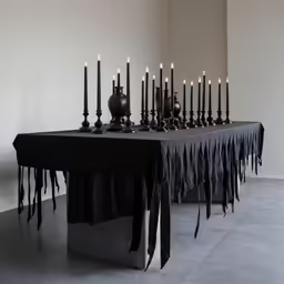 table with black candles on it and several urns