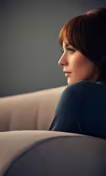 a woman sitting on a couch looking off to the side