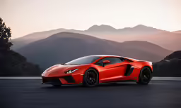 an orange sports car parked in front of mountains