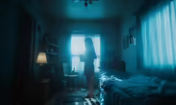 a woman standing in a dimly lit bedroom