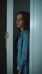 a woman looks through the doorway at the camera