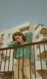 a woman wearing beige pants stands by a railing