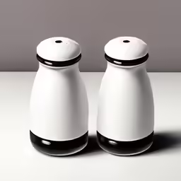 two white salt and pepper shakers sitting side by side