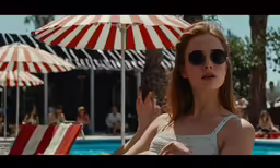 a woman wearing sunglasses sitting in front of a pool