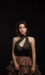 a woman wearing a dark outfit stands with her hands behind her back