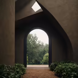 a tunnel through an open concrete archway surrounded by a green bush