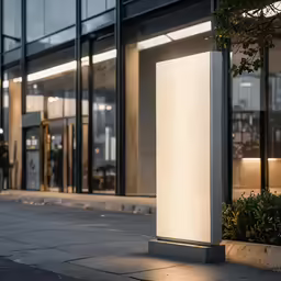 a tall light up sign sitting in front of a tall building