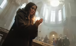 a woman praying in a church with others