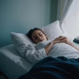 a woman laying in a bed with white sheets