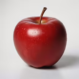 a large red apple sitting on top of a white table