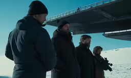 a group of men are gathered on top of the snow