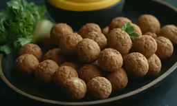 several small, round dessert items are on a tray with fresh fruit and vegetables