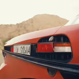 the tail light on a red car is seen in the desert