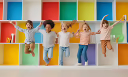 children jumping on colorful bookshelves in playroom