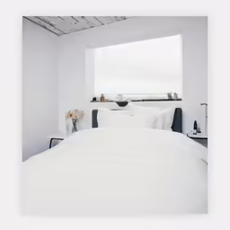 there is a bed with white sheets and white pillows in the room