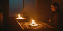 a woman sitting in front of a fire pit