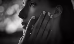 a woman has her hand on her face as she looks away