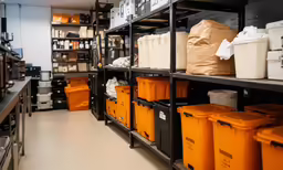 some shelves with orange containers and bins on them