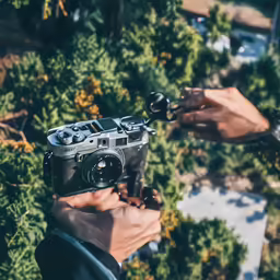 two hands are holding a camera in one hand and another is holding a lens
