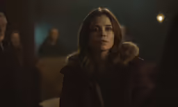 the woman is sitting down while others are looking on