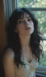 a beautiful young woman in a dress posing by the window