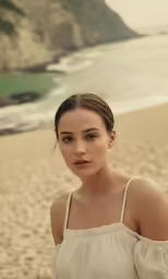 a woman stands in front of the ocean, on the beach