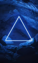 a triangle that is lit up and sitting on rocks