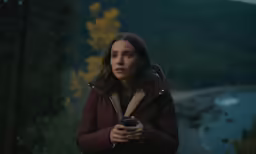 a woman is standing with her hand up looking back at the camera