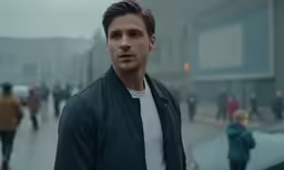 a young man standing in the rain on a street