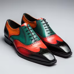 a pair of colorful shoes with a black base,the broncula shoes are made of green, orange and black leather