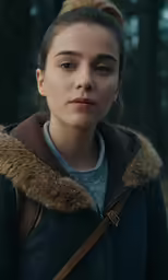 a girl wearing a dark coat in a park