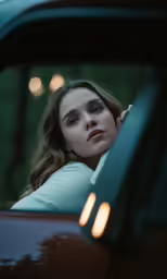 woman looking through window in car with trees in background