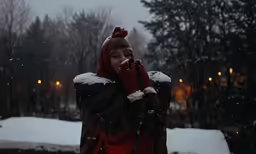 the woman wearing the red hat holds her face up in front of her face while in the snow