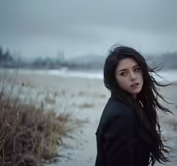 a girl stands on a snowy beach in the winter