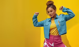 a woman with braids and yellow shirt standing in front of a yellow wall