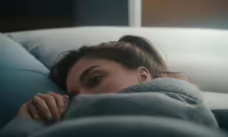 a woman laying on top of a bed covered in blankets