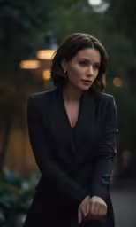 a woman with short hair, sitting down and wearing a black blazer